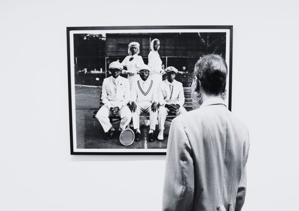 Man standing in front of photo at the Fashion Accounts in Museum Africa Exhibition. 