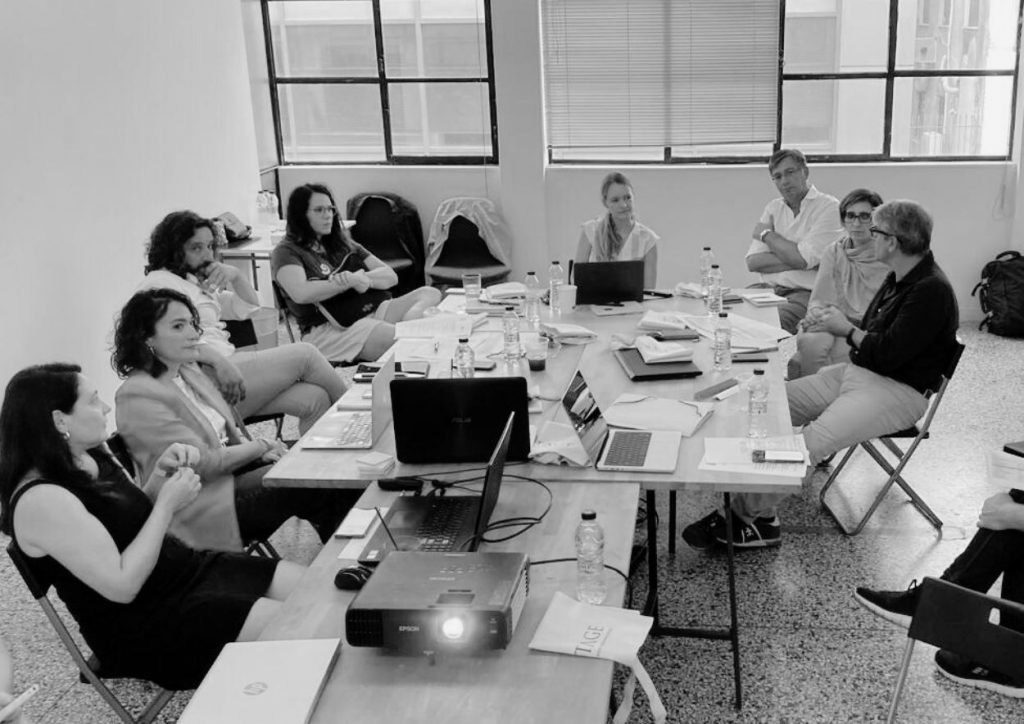 Group of EMPATHS consortium team members gathered around a table with a projector during a project meeting in Athens Greece.