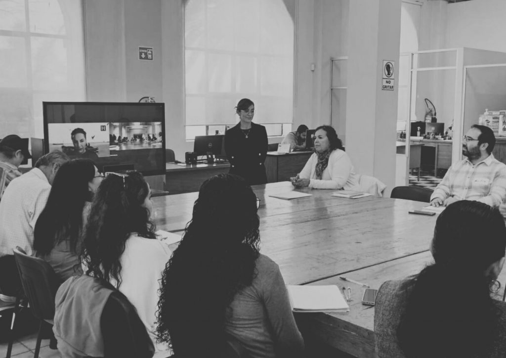 Group of people sitting around tables watching a screen during a training workshop